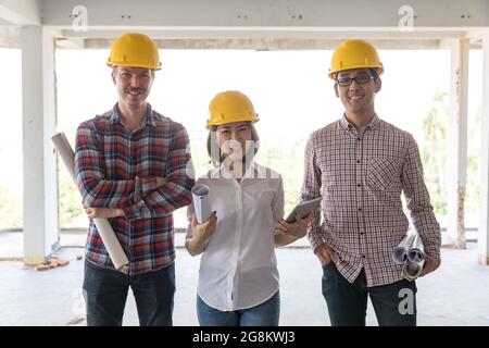 Das Diversity-Team besteht aus einem Ingenieur, einer Frau und zwei Männern, die während der Arbeit auf der Baustelle zusammen standen und vor der Kamera lächelten. Stockfoto