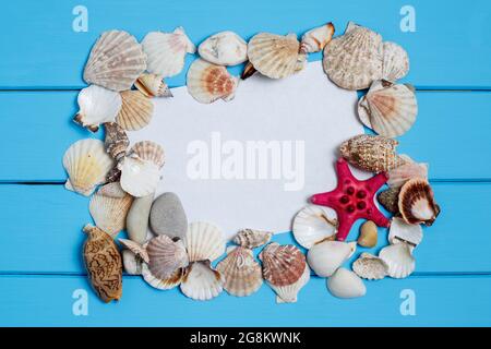 Beach vacation. Different marine items - shells, a starfish, a sheet of paper on blue wooden background. Stockfoto