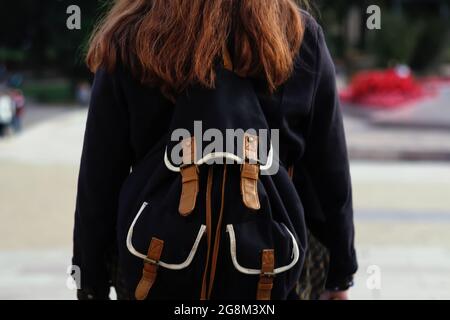 Defokussieren Rückansicht der jungen Brünette Frau zu Fuß. Frau mit Rucksack in der Stadt. Zurück in die Schule, Zurück von College-Student mit Rucksack während der Reise Stockfoto