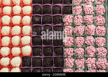 Traditionelle Brigadiere (Schokolade), rote Früchte und weiße Schokolade Brigadiere. In Zeilen organisiert. Stockfoto