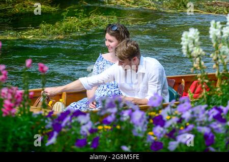 Caterbury, Kent, Juli 21 2021. Ein junges Paar nimmt sich Zeit, die Blumenarrants am Flussufer während einer Punt-Fahrt im Stadtzentrum von Canterbury zu bewundern.Quelle: graham mitchell/Alamy Live News Stockfoto