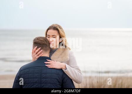 Junge schöne stilvolle Paar im Frühjahr am Strand. Umarmen Sie sich und genießen Sie einen warmen Frühlingsabend.Nahaufnahme. Stockfoto