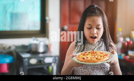 Asiatische kleine Mädchen Vorbereitung hausgemachte Pizza in der Küche mit Überraschung Stockfoto