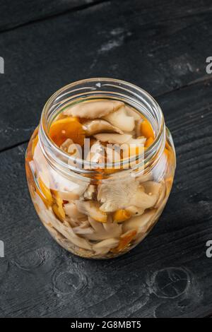 Set mit marinierten Pilzen auf schwarzem Holztisch Stockfoto