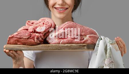 Eine unkenntliche Frau hält ein Holzbrett mit verschiedenen Schnittstücken aus frischem rohem Fleisch Stockfoto