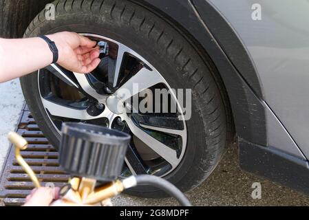 Der Fahrer bläst auf der Tankstelle ein Autorrad auf Stockfoto