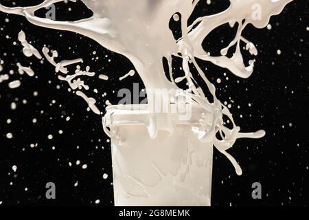 Spritzlack aus einer Dose. Weiße Farbe, die aus Kunststoffbehälter auf schwarzem Hintergrund spritzt Stockfoto
