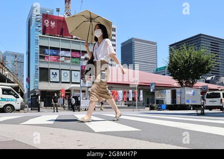 Tokio, Japan. Juli 2021. Eine Frau mit einem Regenschirm überquert die Straße vor dem Tokyo Sports Square, der Heimat des Tokyo 2020 Media Center in Chiyoda-ku, während der Eröffnungszeremonie der Olympischen Spiele 2020 in Tokio. Kredit: SOPA Images Limited/Alamy Live Nachrichten Stockfoto