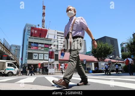 Tokio, Japan. Juli 2021. Während der Eröffnungsfeier der Olympischen Spiele 2020 in Tokio überquert ein Mann die Straße vor dem Tokyo Sports Square, dem Sitz des Tokyo 2020 Media Center in Chiyoda-ku. Kredit: SOPA Images Limited/Alamy Live Nachrichten Stockfoto