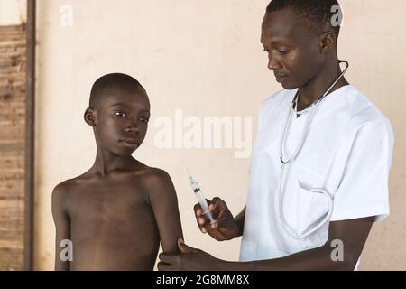 Dies ist ein Bild eines jungen schwarzen afrikanischen Jungen, der bereit ist, von einem afrikanischen Arzt in Bamako, Mali, seinen Impfstoff zu erhalten. Damit soll die Ausbreitung einer de verhindert werden Stockfoto