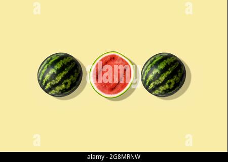 Drei Hälften Wassermelone, isoliert und vor gelbem Sommerhintergrund Stockfoto