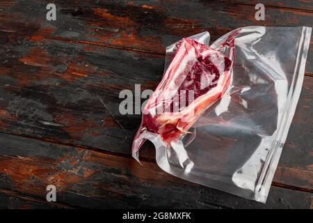 Frisches, riesiges und appetitliches Clubsteak im Vakuumverpackungsset, auf altem dunklen Holztischhintergrund, mit Platz für Text Stockfoto