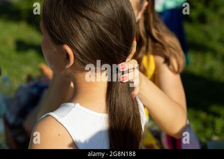 Das Mädchen malt auf das Gesicht des Kindes. Ein Mädchen hält ein Kind fest und malt mit einem Pinsel auf die Haut. Das Kind wartet auf seine Reihe. Stockfoto