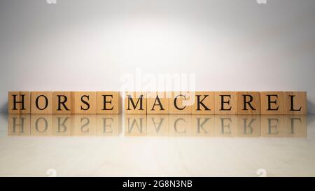 Der Name Pferdemakrele wurde aus hölzernen Buchstabenwürfeln kreiert. Meeresfrüchte und Essen. Nahaufnahme. Stockfoto