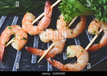 Gegrillte Garnelen Spieße Meeresfrüchte Shelfish, Garnelen Shrimps mit Kräutern Knoblauch auf dem Grill und Gemüsesalat Stockfoto