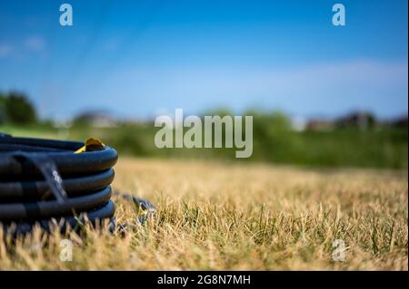 Spule von 1 Zoll Bewässerungsschlauch bereit für die neue Installation auf der Oberseite von braunen und beschädigten trockenen Gras. Stockfoto