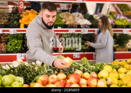 Männlicher Käufer wählt Äpfel im Lebensmittelgeschäft Stockfoto