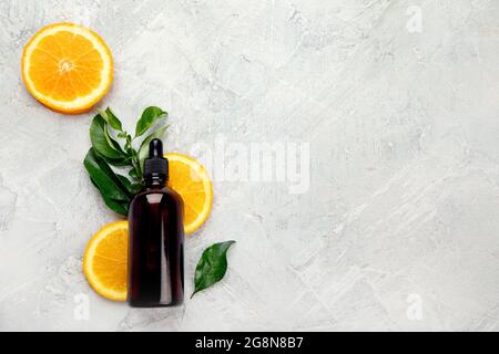 Flasche ätherisches Aromaöl mit Orangen und Blättern auf hellgrauem Hintergrund. Draufsicht, flach liegend, Kopierbereich Stockfoto