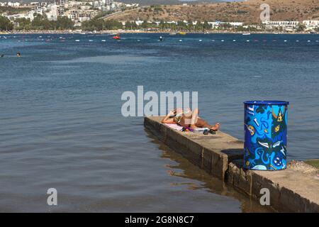 Mugla, Türkei. Juli 2021. Am Strand von Bodrum kann man eine Frau beim Sonnenbaden beobachten.der Stadtbezirk von Bodrum, Mu?la, einer der beliebtesten touristischen Bezirke der Türkei, zieht weiterhin Touristen aus der ganzen Welt an. Die meisten dieser Touristen bestehen aus Russen, Deutschen und Asiaten. Auf Eid El-Adha machten türkische Touristen Bodrum aufgrund der Woche der religiösen Feiertage zu einer ihrer meistbesuchten Regionen. Kredit: SOPA Images Limited/Alamy Live Nachrichten Stockfoto