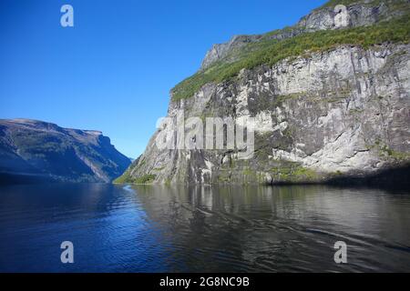Fahrt entlang des Geiranger Fjords. Schöne Landschaft mit Reflexionen der Berge im Wasser an einem ruhigen Sommertag, norwegischen Fjorden, Norwegen. Stockfoto