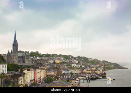 Blick auf den Hafen und die Stadt Cobh, Irland. Farbenfrohe Gebäude säumen den Hang. Mit einer großen Kirche über der Stadt mit Blick auf das Meer. Stockfoto