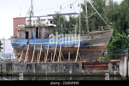 Rostock, Deutschland. Juli 2021. Auf dem Gelände der ehemaligen Neptun-Werft liegen zwei ehemalige Fischkutter an Land. Der ehemalige Fischkutter 'Barth' (l) aus Warnemünde wurde hierher geschleppt und an Land gebracht, weil er kurz vor dem Untergang stand, vor dem ehemaligen Fischkutter 'Wernigerode', der wochenlang auf dem Boden des Stadthafens lag, bevor er gerettet und hierher transportiert wurde. Ob die Fräser verschrottet werden, wird wahrscheinlich noch geklärt, aus wirtschaftlicher Sicht hätten sie wahrscheinlich keine Zukunft mehr. Quelle: Bernd Wüstneck/dpa-Zentralbild/ZB/dpa/Alamy Live News Stockfoto
