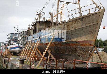 Rostock, Deutschland. Juli 2021. Auf dem Gelände der ehemaligen Neptun-Werft liegen zwei ehemalige Fischkutter an Land. Der ehemalige Fischkutter 'Barth' (l) aus Warnemünde wurde hierher geschleppt und an Land gebracht, weil er kurz vor dem Untergang stand, vor dem ehemaligen Fischkutter 'Wernigerode', der wochenlang auf dem Boden des Stadthafens lag, bevor er gerettet und hierher transportiert wurde. Ob die Fräser verschrottet werden, wird wahrscheinlich noch geklärt, aus wirtschaftlicher Sicht hätten sie wahrscheinlich keine Zukunft mehr. Quelle: Bernd Wüstneck/dpa-Zentralbild/ZB/dpa/Alamy Live News Stockfoto
