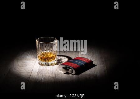 Glas Scotch Whisky und eine hippe Flasche auf einer Holzoberfläche auf schwarzem Hintergrund mit Platz für Text Stockfoto