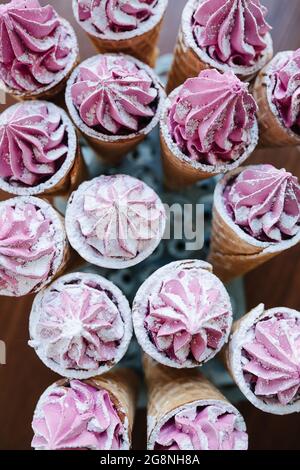 Draufsicht auf süße Waffelkegel mit rosa Creme auf einem besonderen Stand Stockfoto