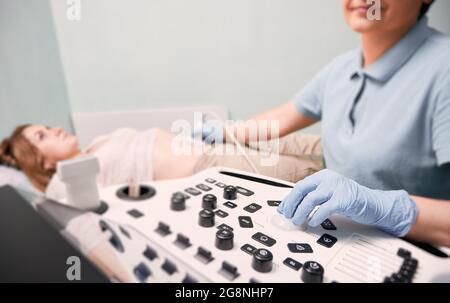 Konzentrieren Sie sich auf die Hand des Arztes in sterilen Handschuhen, um weibliche Patienten mit Ultraschallscanne zu untersuchen. Ultraschalluntersuchung durch einen Ultraschalluntersuchung. Konzept des Gesundheitsgedankens Stockfoto