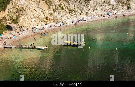 Touristen, die an einem sonnigen Tag mit klarem Wasser auf eine Bootsfahrt an der Jurassic Coast nach Durdle Door mit der Lulworth Rib Ride Company fahren. Stockfoto