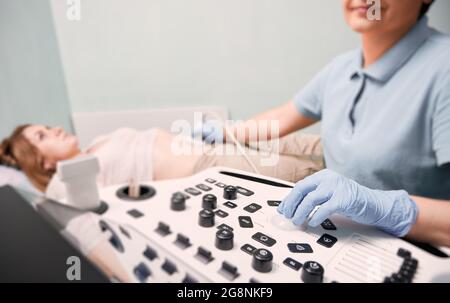 Konzentrieren Sie sich auf die Hand des Arztes in sterilen Handschuhen, um weibliche Patienten mit Ultraschallscanne zu untersuchen. Ultraschalluntersuchung durch einen Ultraschalluntersuchung. Konzept des Gesundheitsgedankens Stockfoto