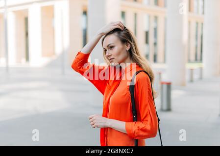 Kaukasisches Mädchen, das mit einer Tasche auf der Schulter durch die Stadt läuft Stockfoto
