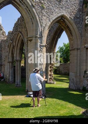 Creake Abbey, die Ruinen einer Augustiner-Abtei aus dem Jahr 1206, North Creake, Norfolk, Großbritannien; im Vordergrund Künstler bei der Arbeit Stockfoto