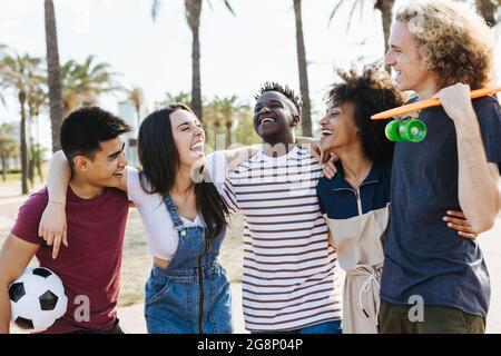 Glückliche Freunde aus verschiedenen Kulturen und Rennen lachen und Spaß im öffentlichen Park haben - Multi-ethnische Gruppe von jungen Menschen genießen in den Sommerferien Stockfoto