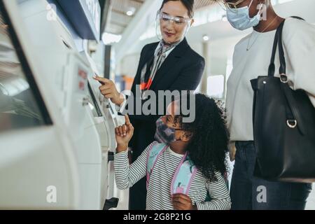 Der Flughafenbegleiter half der zweiköpfigen Familie beim Check-in. Junge Mädchen und Frauen, die dem Flughafenpersonal am internationalen Terminal helfen. Stockfoto