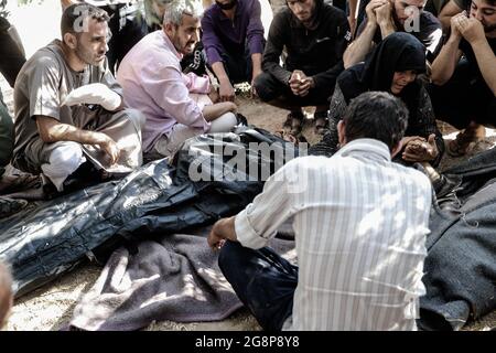 Iblin, Syrien. Juli 2021. Verwandte und Freunde sitzen neben den Leichen der Opfer, die bei einem Raketenbeschuss der syrischen Regierung auf dem Dorf Iblin in Idlib getötet wurden. Quelle: Anas Alkharboutli/dpa/Alamy Live News Stockfoto