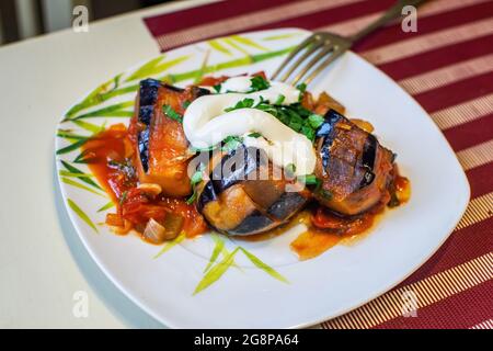 Ratatouille. Saftig geschmorte Aubergine mit Gemüse und saurer Rahm auf einem weißen Teller. Stockfoto