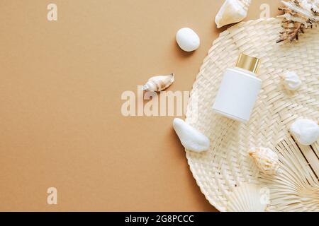 Sonnencreme-Lotion Flasche und Muscheln auf sandigen Hintergrund. Flach liegend, Draufsicht, Overhead. Stockfoto