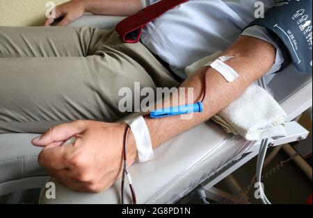 Rostock, Deutschland. Juli 2021. Clemens Schafmayer, leitender Chirurg und Direktor der Klinik und Poliklinik für Allgemeine, Viszerale, Thorax-, Gefäß- und Transplantationschirurgie, spendet Blut am Blutkreislauf von Unimedicine. Die Aktion ist Teil eines Appells der Institution, die um Blutspenden bittet. Aufgrund des akuten Mangels an Blutspenden müssen die Operationen jeden Tag verschoben werden, die Corona-Krise hat den normalen Blutmangel für einen Sommer auf das Maximum verschärft. Quelle: Bernd Wüstneck/dpa-Zentralbild/ZB/dpa/Alamy Live News Stockfoto