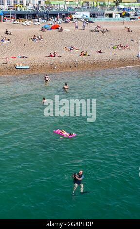 Brighton UK 22. Juli 2021 - Sonnenanbeter und Schwimmer machen das Beste aus einem weiteren schönen heißen sonnigen Tag am Brighton Beach, aber das Wetter wird am Wochenende kühler und unruhiger : Credit Simon Dack / Alamy Live News Stockfoto