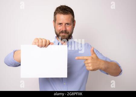 Porträt eines glücklich lächelnden jungen Geschäftsmanns mit leerem Schild auf weißem Hintergrund. Stockfoto