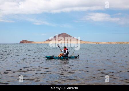 Mann paddeln ein kleines Fischerkajak im Atlantischen Ozean, beliebte Wasseraktivitäten, die normalerweise praktiziert werden, wenn der Ozean ruhig und ohne hohe Wellen ist, Teneriffa Stockfoto