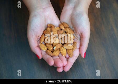 Frau mit einer Handvoll Mandeln, den essbaren Samen von Prunus dulcis, ideal für eine Portion Nüsse für einen gesunden natürlichen Snack Stockfoto