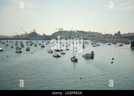 Boote, die in der Falmout Bucht in der Nähe des Hafens mit Land im Hintergrund festgemacht sind Stockfoto