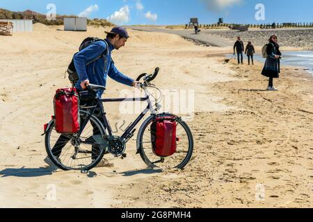 Ein Mann, der mit dem Fahrrad an der niederländischen Küste unterwegs ist, um Urlaub in Zeeland, Westkapelle, zu machen Stockfoto