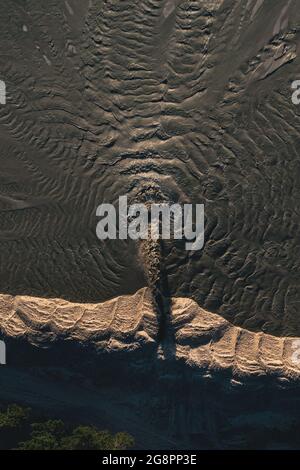 Schmutzwasserfluss mit Sand während der Sandgewinnung. Wellen verteilen sich auf der Oberfläche des Steinbruchs zur Gewinnung von Flusssand. Ableitung von Schadstoffen in den Fluss. Stockfoto