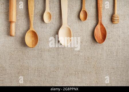 Bastellöffel aus verschiedenen Holzarten liegen in einer Reihe auf einem Hanf-Quappen-Stoff Stockfoto