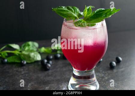 Blueberry Basil Lemon Gimlet Cocktail garniert mit frischem Basilikum: Ein Wodka-Gimlet-Cocktail mit Heidelbeeren, Zitrone und Basilikum Stockfoto