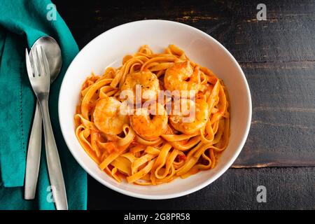 Schüsseln mit Garnelen und Pasta in Tomatensahnesauce: Schüsseln mit Garnelen und Fettuccine Nudeln in einer cremigen Tomatensoße Stockfoto